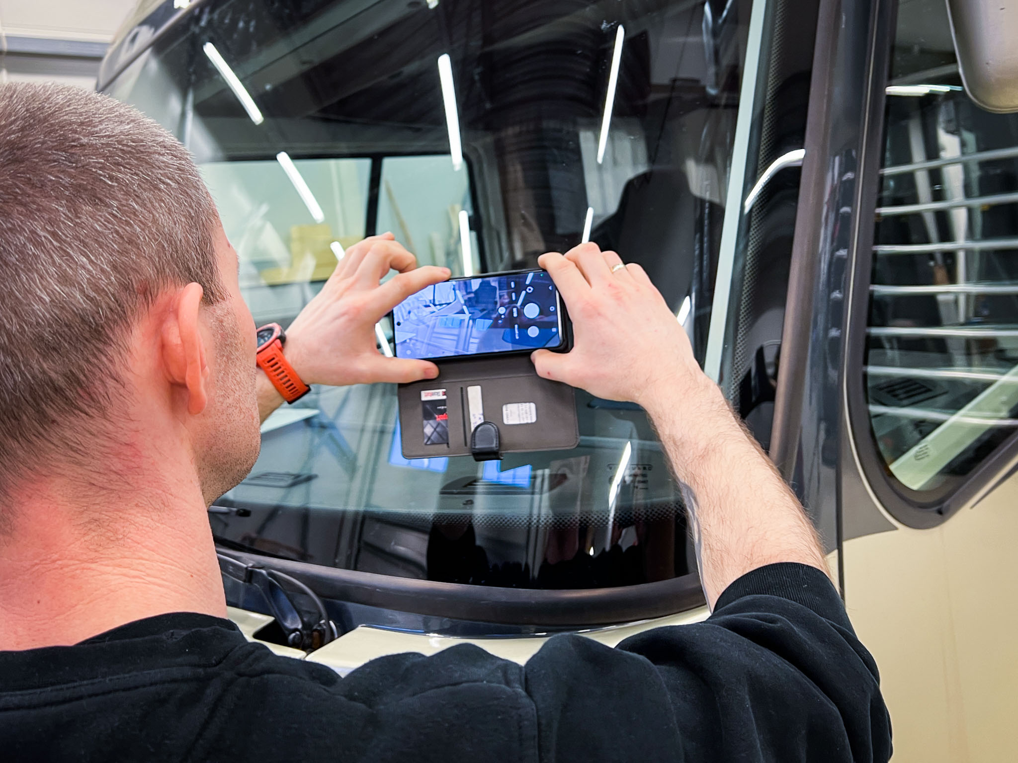 Noen tar et mobilbilde av frontruteskaden på bobilen