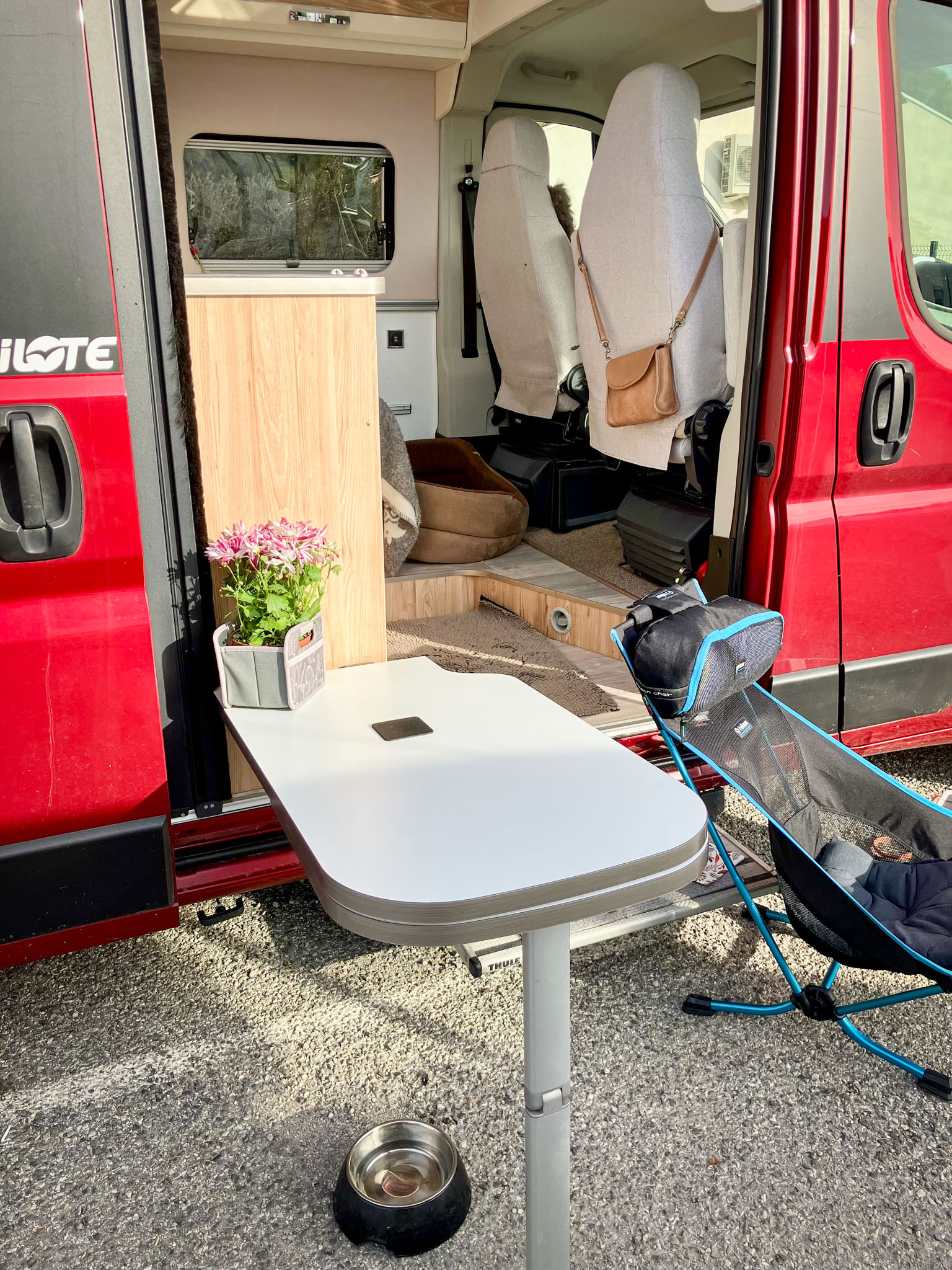 Bildet viser et utbrettbart bord utenfor en rød campervan
